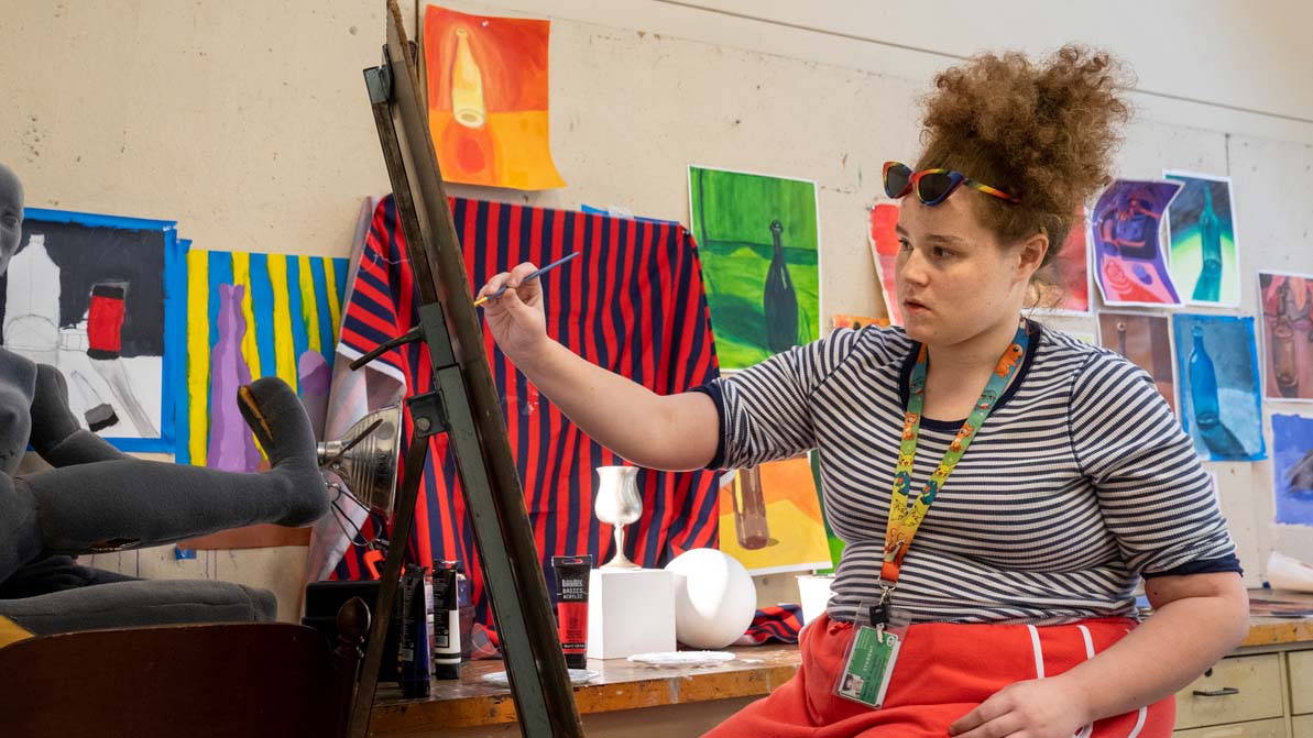 A 첥 paints using an easel